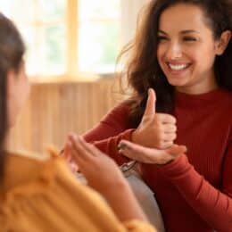 Inclusive language in technical documentation is symbolized by a photo of two persons talking in sign language, one of them signing "help".