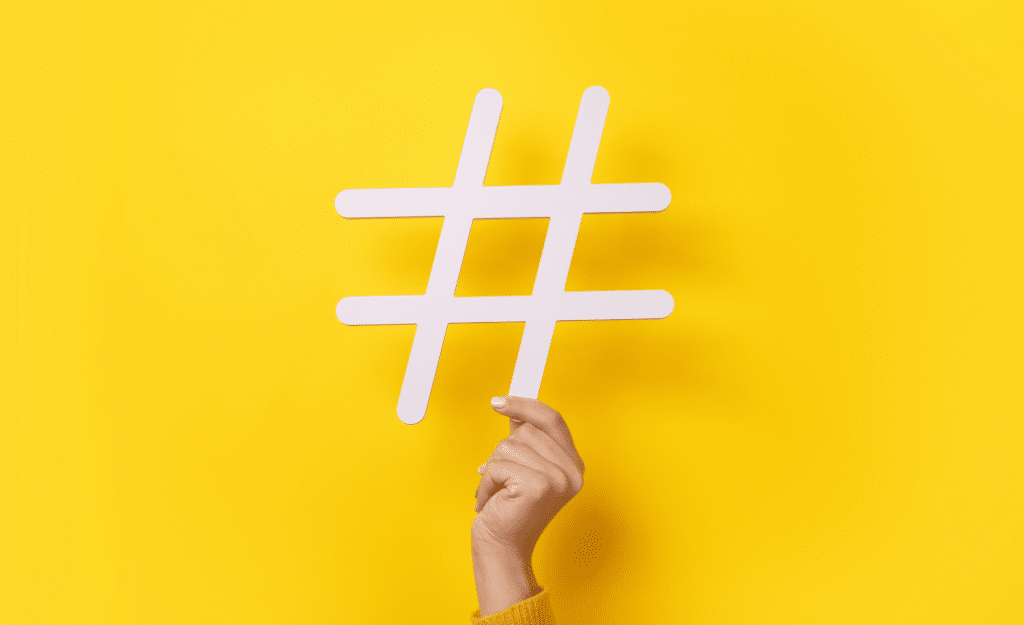 Yellow background and a hand holding up a # sign. This symbolizes web content.