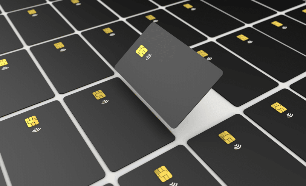 Numerous black credit cards with golden chips, one card angled and raised above the others.