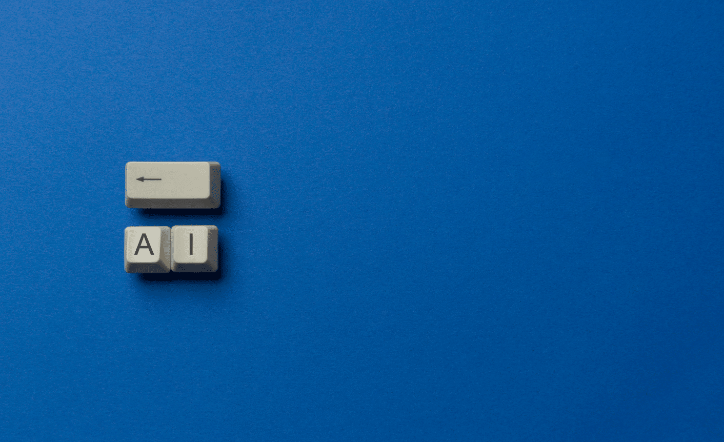 On a dark blue background are three old-fashioned keyboard keys. One with an arrow pointing backwards and the other two with the letters "A" and "I" on them.