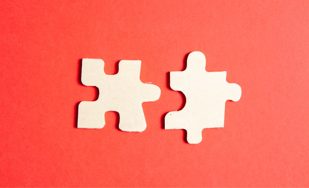 Two white puzzle pieces on a red background to symbolize the unification of two different content operations after a merger and acquisition.