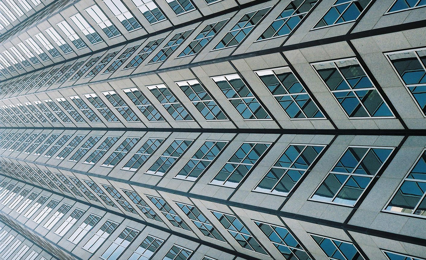 A close-up view of a high-rise building exterior with numerous windows and a geometric pattern.