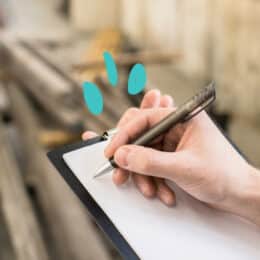 A hand starting to write on a clipboard symbolizes controlled languages like Simplified Technical English.