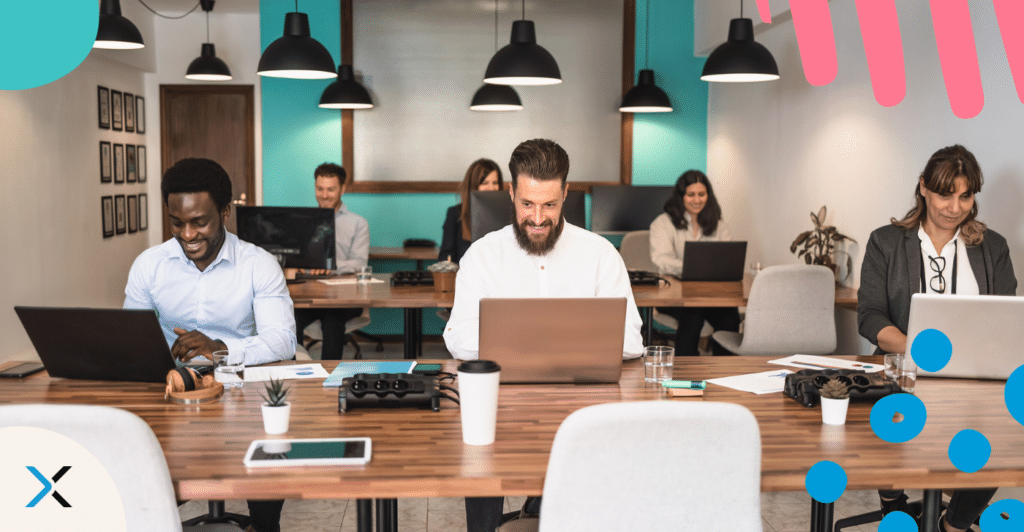 People working on laptops at a desk respresenting outsourcing non-native writers to create content.