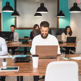 People working on laptops at a desk respresenting outsourcing non-native writers to create content.