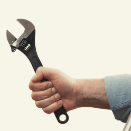 A hand holding a wrench protruding from a screen symbolising a technical writing checker aimed at helping technical teams write better content.